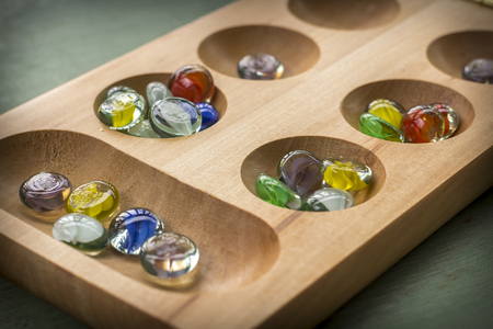 Traditional Mancala boardgame with glass pieces on wooden tableの写真素材