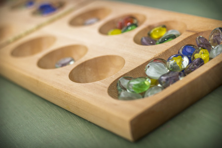 Traditional Mancala boardgame with glass pieces on wooden tableの写真素材