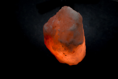 Glowing pink himalayan sea salt lamp on dark backgroundの写真素材