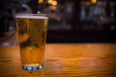 Foamy glass of cold beer dark color with lots of hopsの写真素材
