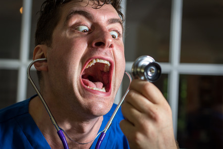 Crazy lunatic male nurse yells into his own stethoscopeの写真素材