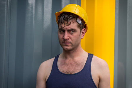 Young handsome construction worker in tank top and yellow hatの写真素材