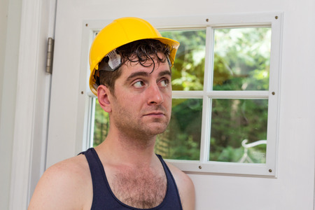 Young handsome construction worker in tank top and yellow hatの写真素材