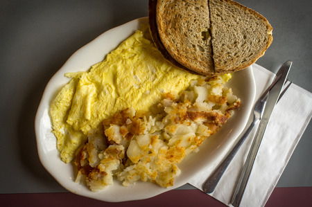 Cheese and egg omelette with home fries and toasted rye breadの写真素材