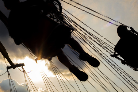 Fairground swing ride at dusk with sunset silhouette