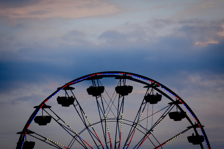 Silhouette summer carnival ferris wheel against sunset sky
