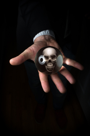 Holding magic crystal ball with skull predicting deathの写真素材