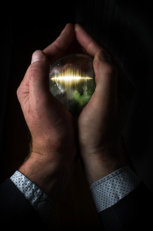 Holding magic crystal ball containing sound waveの写真素材