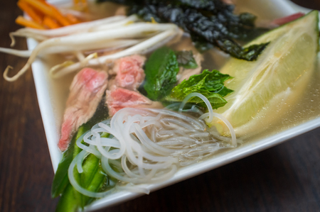 Traditional Vietnamese pho beef noodle soup garnished with mint leavesの写真素材