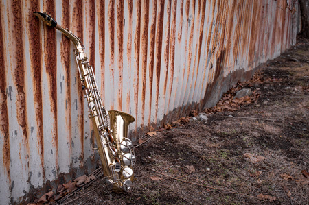 Jazz musical instrument saxophone with rusty fence backgroundの写真素材