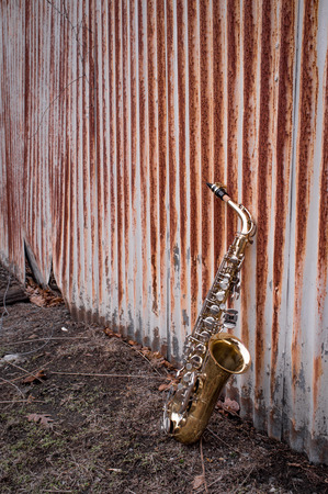 Jazz musical instrument saxophone with rusty fence backgroundの写真素材