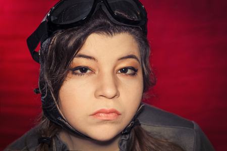 Girl wearing aviator hat and goggles makes silly facial expression from strong windの写真素材