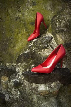 Red high heel shoes mossy green rocks with nobody wearing themの写真素材