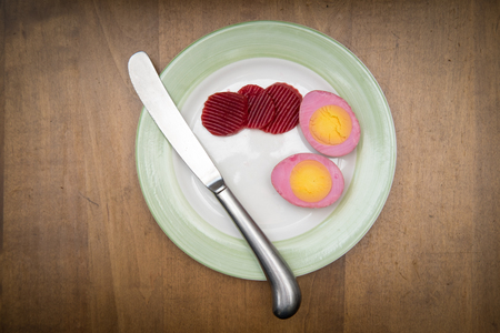 Sliced organic pickled beet eggs on wooden tableの写真素材