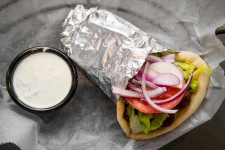Fresh and healthy falafel with tzatziki tomato red onion and iceberg lettuce in pita breadの写真素材