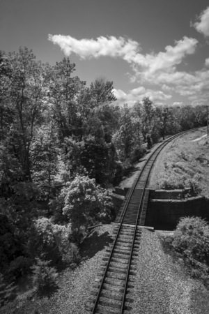Black and white train tracks beside bridge landscapeの写真素材