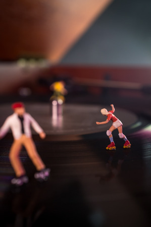 Miniature roller skating figures on vintage vinyl record in macro closeup