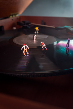 Miniature roller skating figures on vintage vinyl record in macro closeupの写真素材