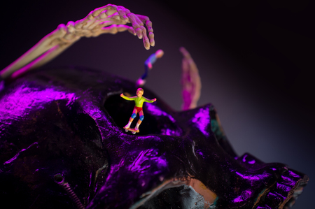 Skateboarding figurines evade giant monster skeleton armsの写真素材