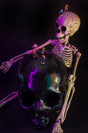 Roller skating and skateboarding figurines evade giant skeletonの写真素材