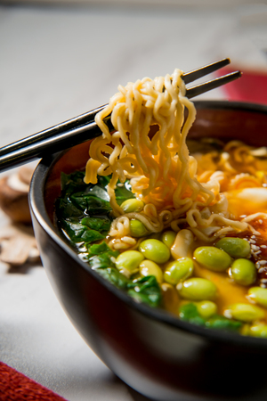Spicy edamame and narutomaki spiral ramen noodle soup with runny fried eggの写真素材