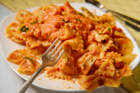 Farfalle bow tie pasta in creamy vodka tomato sauce with grilled chicken and green peasの写真素材