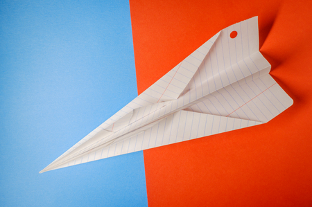 Paper air plane closeup on colorful blue and orange backgroundの写真素材