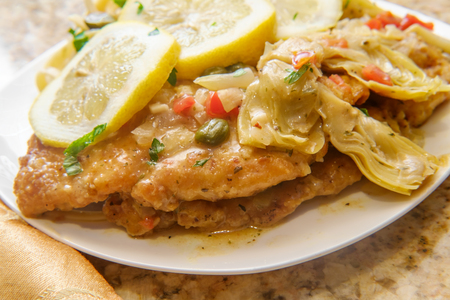 Italian chicken piccata schnitzel with artichoke hearts served on fettuccineの写真素材