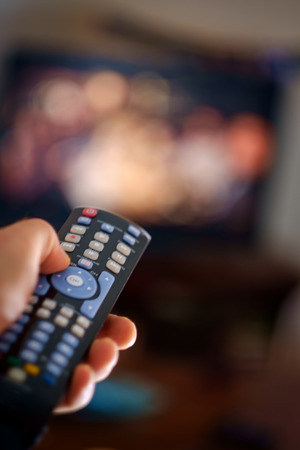 Close up of remote in hand with shallow depth of field during television watching