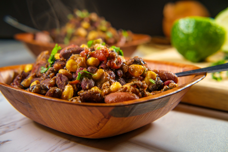 Hot and spicy bowls of Chili con carne on marble kitchen table with ingredientsの写真素材