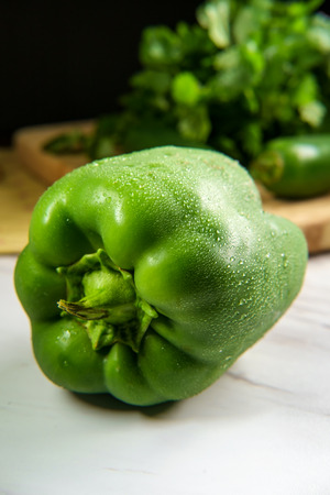 Fresh juicy green bell pepper on marble counter top in kitchenの写真素材