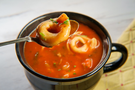 Fresh hot tortellini tomato soup on marble kitchen tableの写真素材