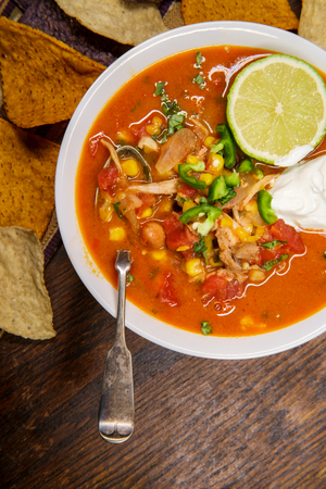 Hearty and spicy tortilla soup with hot peppers and orange purple and white multicolored torttilla chipsの写真素材