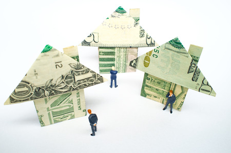 Miniature figurine businessmen and origami paper money houses for real estate and housing market...