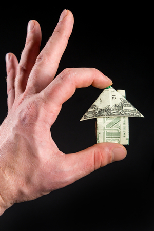 Hand holds origami paper money house for real estate and housing market conceptの写真素材