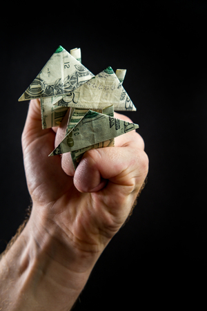Hand holds origami paper money house for real estate and housing market conceptの写真素材