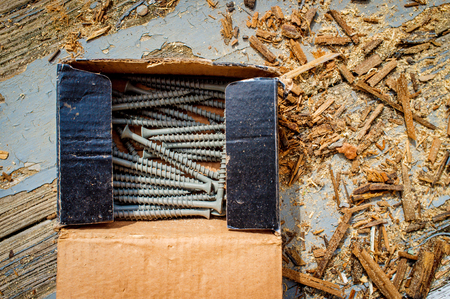 Box of contracting deck screws with sawdust on worn wooden porchの写真素材