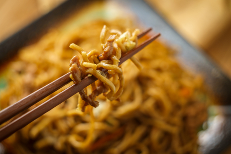 Eating Chinese pork lo mein noodles with chopsticksの写真素材