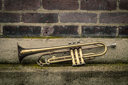Old rusty Jazz instrument trumpet leaning against brick wall building outside clubの写真素材