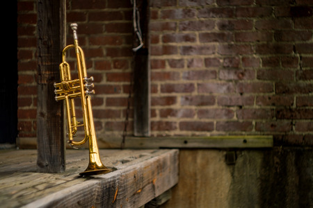 Old rusty Jazz instrument trumpet leaning against brick wall building outside clubの写真素材