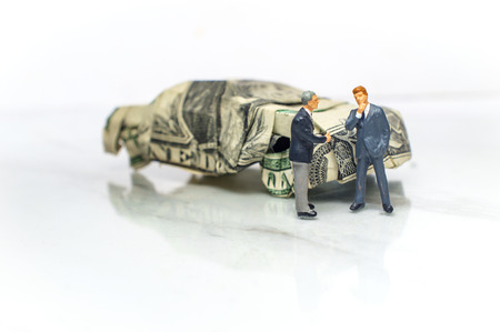 Miniature businessman makes a deal with a car salesman for expensive sports car