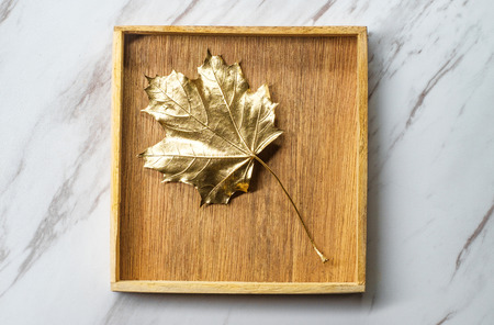 Golden Christmas maple leaf on marble table in wooden boxの写真素材