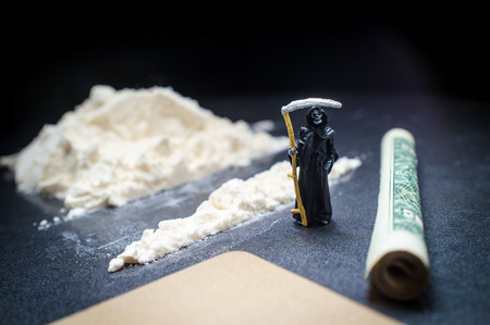 Grim reaper stands by pile of cocaine as metaphor warning of the dangers of drug addiction