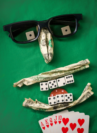 Silly bad poker face metaphor made from various gambling items including money dice cards and poker chipsの写真素材