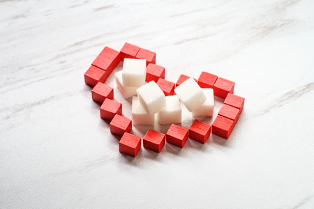 Diabetes bloodsugar and heart health concept with sugar cubes inside red wooden blocksの写真素材