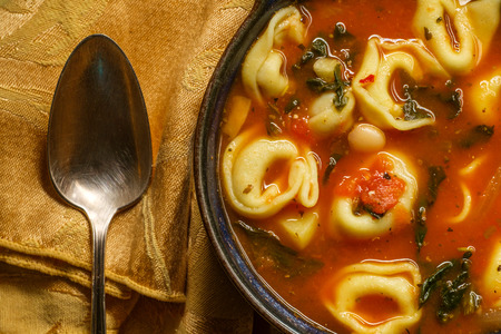 Fresh hot tortellini tomato soup with potatoes mushrooms and cannellini beansの写真素材