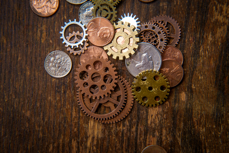 Pile of gears cogs and coins mixed together as business finance conceptの写真素材