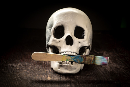 Starving artist human skull eating or holding paintbrush in mouth