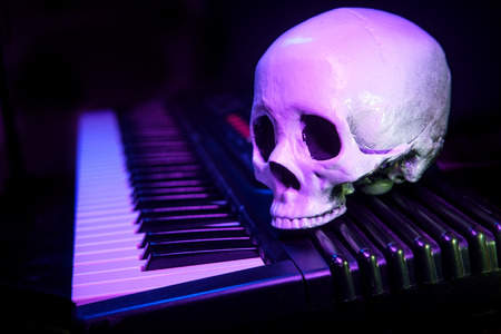 Human skull on electric piano keyboard for scary musical performance