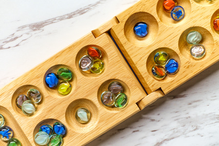 Traditional Mancala boardgame with glass pieces on marble tableの写真素材